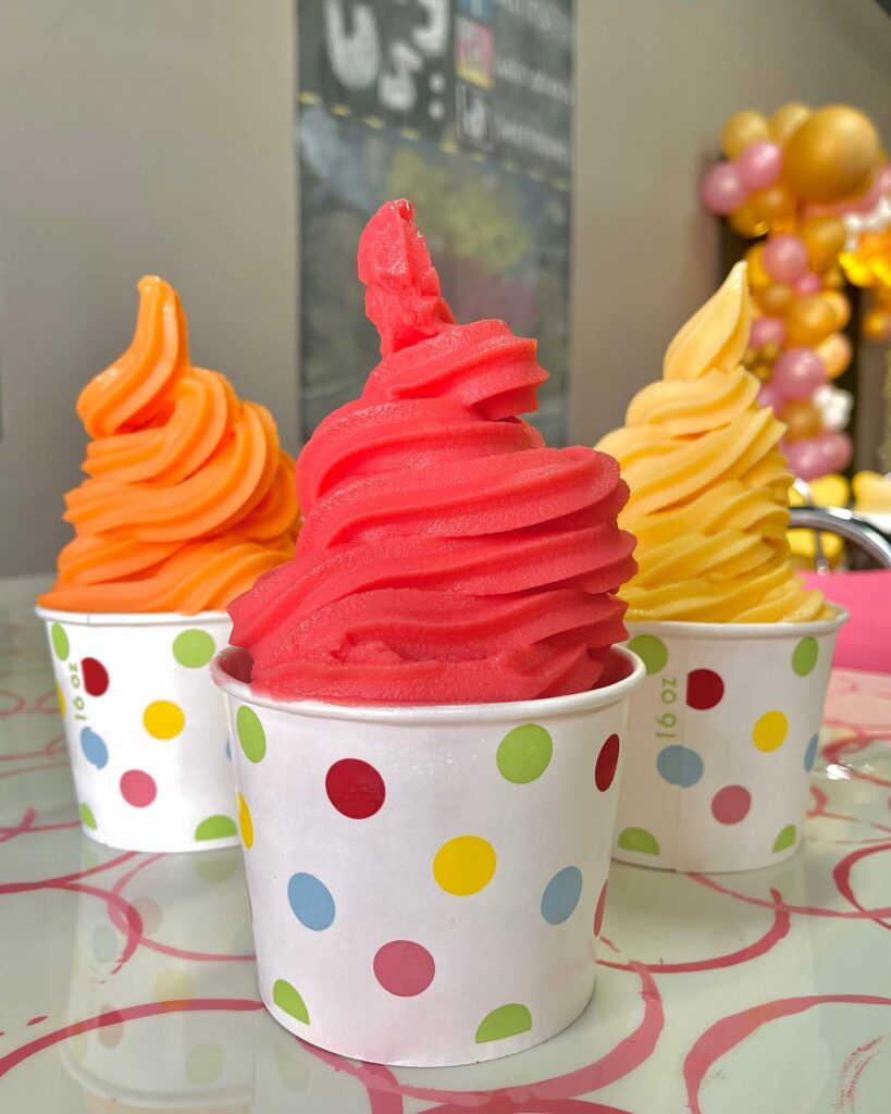 Three bowls of soft serve ice in orange, red and yellow